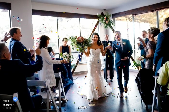 Foto: <a href="https://www.wpja.com/contests/2019-v01/best-wedding-photographers/2435126"> Trent Gillespie - Silverthorne Colorado </a> The Pines at Genesee - Trauungszeremonie im Innenhof - Als Ehemann und Ehefrau auf der Insel zu einem Ballwurf von ihren Gästen.