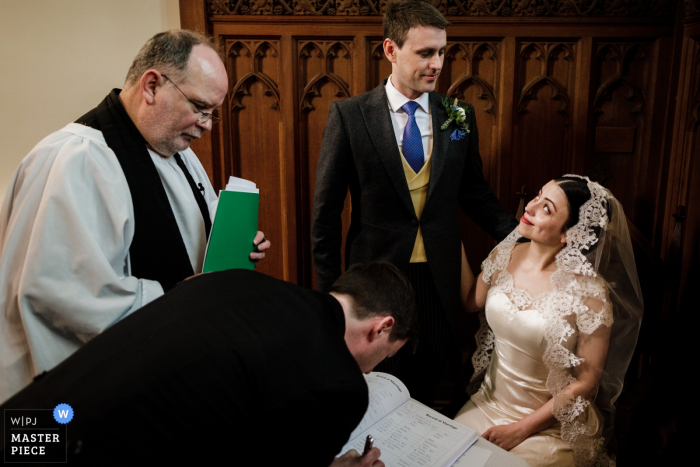 Clonabreany House, Ireland wedding photographer - Newlyweds exchange a look over signing of the marriage register 