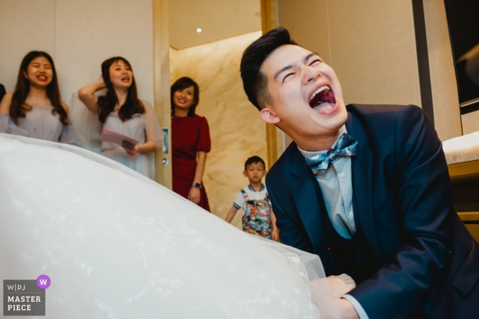 Fotografía de bodas en FUZHOU, CHINA - LA AYUDA DE AYUDA DE GROOM PONE LOS ZAPATOS DE BODA.