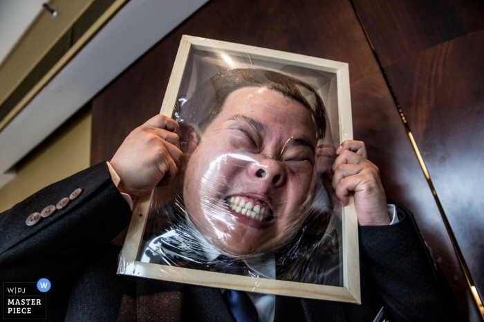 Un ospite partecipa a una partita, spaccandogli la faccia in plastica in questo matrimonio di Pechino in questa foto di un fotografo di matrimoni in Cina.