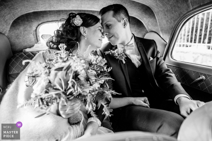 Foto en blanco y negro de la novia y el novio que tienen un momento de tranquilidad solo en el asiento trasero del automóvil