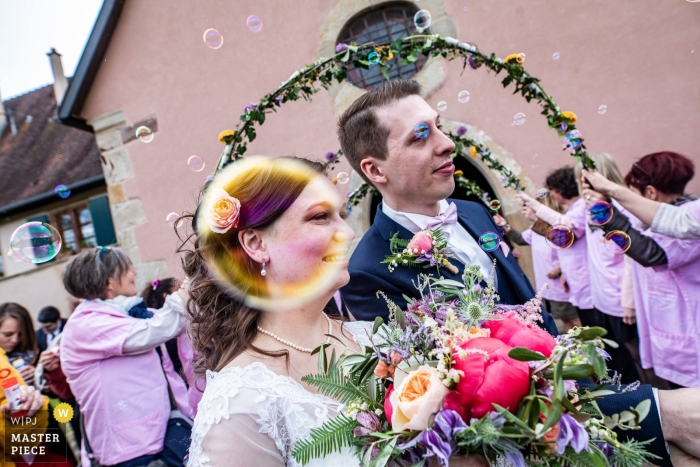 Photo by: <a href="https://www.wpja.com/contests/2019-v04/best-wedding-photographers/2462816">Nicolas Bernard - Ammerschwihr </a> This Rouffach, France wedding photographer has captured a photo of the bride through a bubble as she walks with her groom.