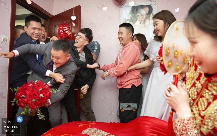 Photo: <a href="https://www.wpja.com/contests/2019-v04/best-wedding-photographers/2465956"> Binbin Wong - La ville de Xining </a> Le marié et les garçons d’honneur ont fait irruption par la porte, immédiatement pris par les parents et les amis de la mariée sur cette photo par un photographe de mariage à Qinghai, Chine.