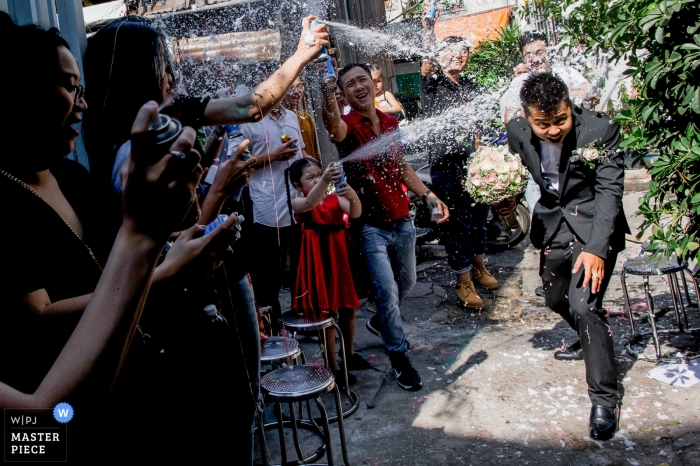 Photo by: <a href="https://www.wpja.com/contests/2019-v04/best-wedding-photographers/2467621">Huy Nguyen - Ho Chi Minh </a> Photo of the groom making his way past guests as they spray him with foam spray by a Ho Chi Minh, Vietnam wedding photographer.