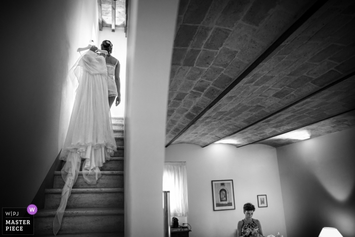 Foto por: <a href="https://www.wpja.com/contests/2019-v04/best-wedding-photographers/2469971"> Samuele Ciaffoni - Ancona Ancona </a> Foto en blanco y negro de una mujer que lleva el vestido de novia de la novia arriba sobre su hombro en Las Marcas por un fotógrafo de bodas de Italia.