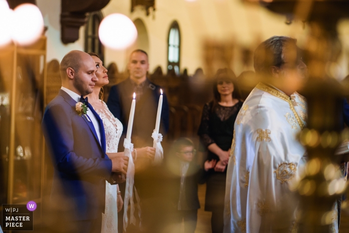 Photo by: <a href="https://www.wpja.com/contests/2019-v04/best-wedding-photographers/2470971">Boni Bonev - Sofia Sofia</a> Sofia, St. Nedelia church photography - The ceremony with the bride and groom holding candles with her eyes fixed upwards.
