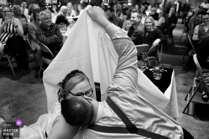 Photo: <a href="https://www.wpja.com/contests/2019-v05/best-wedding-photographers/2473961"> Tara Theilen - Carson City dans le Nevada </a> Miner's Foundry, Nevada City, Californie Photographe de mariage - Photo du couple qui soulève sa nappe pour s’embrasser sous la table, dans la tradition danoise.