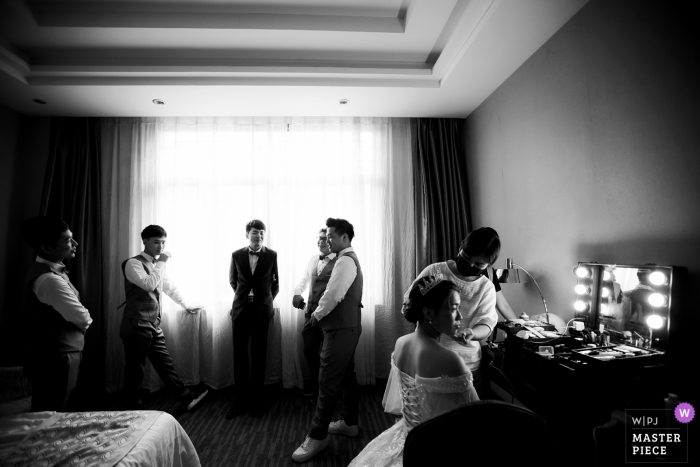 Photo by: <a href="https://www.wpja.com/contests/2019-v05/best-wedding-photographers/2476681">Zhongkun Zhang - Sanming </a> Fujian hotel room wedding day photography - The bride dresses up and the groomsman waits