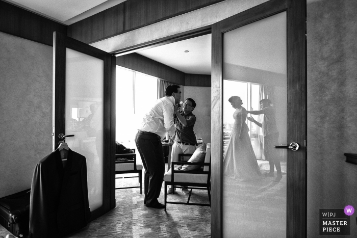 De het huwelijksfotograaf van Bangkok ving deze zwart-witte foto van de bruid die haar kleding krijgt die vóór de ceremonie wordt gestoomd