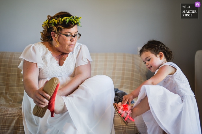 Photo by: <a href="https://www.wpja.com/contests/2019-v05/best-wedding-photographers/2478026">Franck Petit - Serignac sur Garonne </a> Lot-et-Garonne wedding photographer captured this photo of a bride wearing a floral crown putting on red sandals, as an identically dressed flower girl tries to do the same
