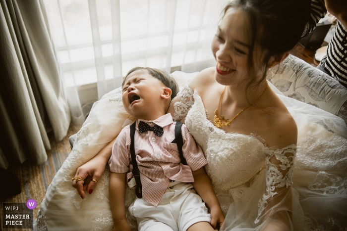Photo by: <a href="https://www.wpja.com/contests/2019-v05/best-wedding-photographers/2478071">Kai Xiao - Sanming </a> A bride holds a crying toddler in this photo captured by a Sanming wedding photographer