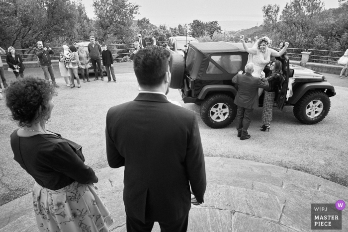 Photo by: <a href="https://www.wpja.com/contests/2019-v05/best-wedding-photographers/2478451">Andrea Bagnasco - Varazze Savona</a> Varazze, Italy black and white wedding photo showing the bride arriving at church while groom stands waiting
