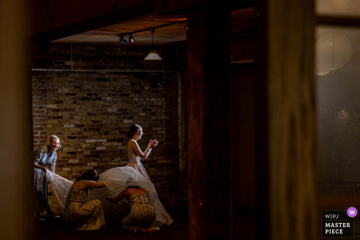 Foto door: <a href="https://www.wpja.com/contests/2019-v05/best-wedding-fotografen/2478906"> Victoria Sprung - Chicago Illinois </a> Rockford, IL - Prairie Street Brewing Wedding Venue Fotografie van de bruid die zich klaar maakt met vrienden / familie.