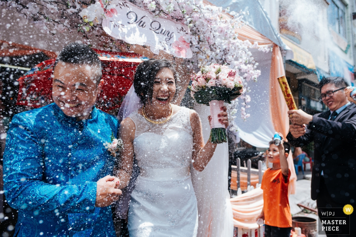 Deze foto van de bruid en de bruidegom die met confettien na hun ceremonie worden overladen werd gevangen door een Ho Chi Minh huwelijksfotograaf