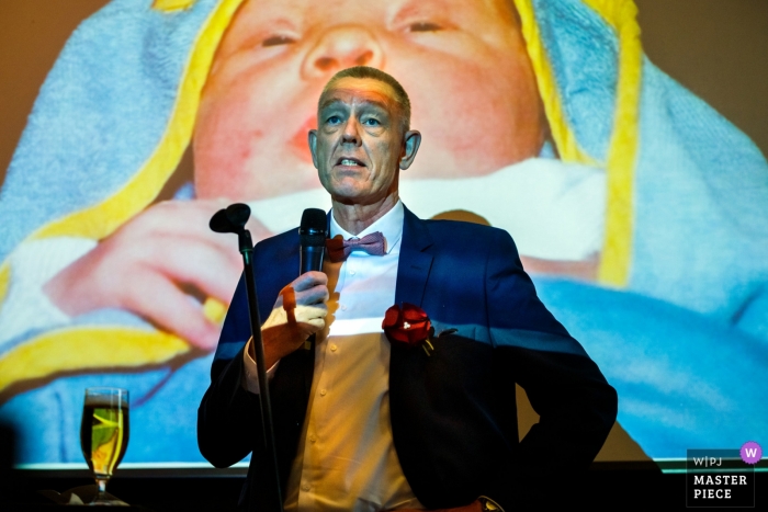 Photo by: <a href="https://www.wpja.com/contests/2019-v05/best-wedding-photographers/2481226">Indra Simons - Enschede Overijssel</a> Osnabruck wedding photographer | Picture during the speech by father of the bride with slideshow behind him