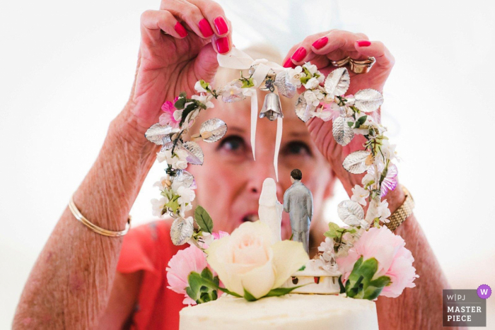 Photo by: <a href="https://www.wpja.com/contests/2019-v05/best-wedding-photographers/2481336">David Weightman - Guildford Surrey</a> The Mill House Hotel, Berkshire, UK Weddings - Photographic Image showing Granny attaching the family cake topper to the wedding cake