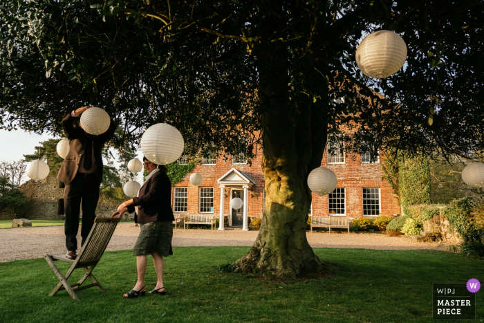 Westenhanger Castle, Kent wedding photograph showing a man putting up Lantern in a tree