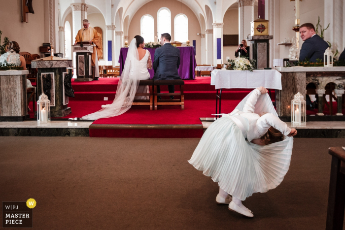 Photo by: <a href="https://www.wpja.com/contests/2019-v05/best-wedding-photographers/2482851">Kevin Kheffache - Dun Laoghaire Dublin</a> Salthill Galway Wedding Photo showing the Page girl playing in the church during the ceremony