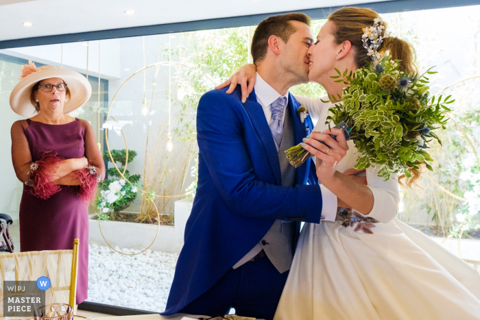 Photo by: <a href="https://www.wpja.com/contests/2019-v05/best-wedding-photographers/2483856">Toni Miranda - Alcoy Alicante</a> Alicante wedding photographer captured this beautiful photo of the bride and groom kissing as the mother of the groom watches nearby