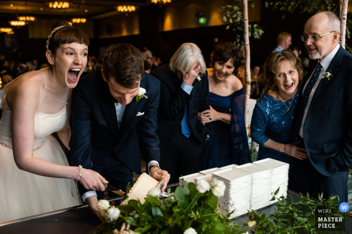 Foto del ricevimento di nozze di Edgewater Hotel - La torta è caduta durante il taglio della torta e tutti ridono - Madison, WI fotografia di matrimonio