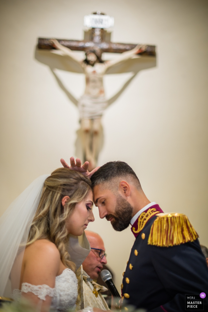 Photo by: <a href="https://www.wpja.com/contests/2019-v06-photography-competition/best-wedding-photographers/2486086">Alessandro Di Noia - Gussago Brescia</a> Mondragone (Ce) - Parrocchia di San Michele Arcangelo Wedding Photography - A solemn moment of the ceremony for the bride and groom with praying priest.