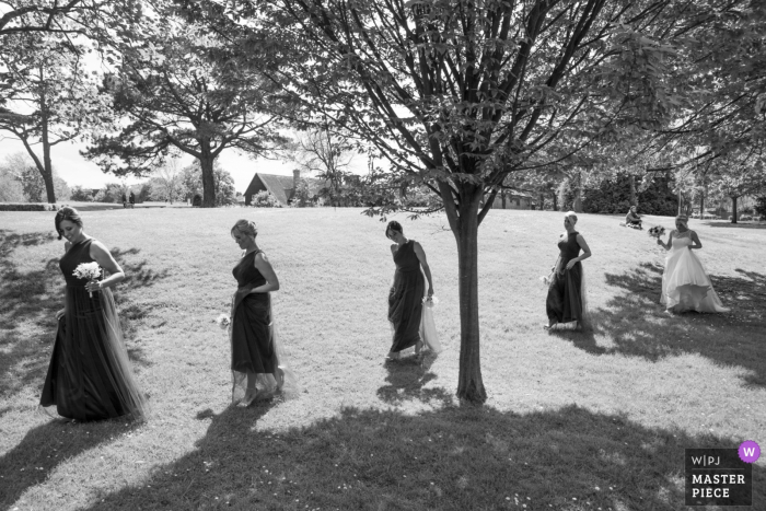 Photo by: <a href="https://www.wpja.com/contests/2019-v06/best-wedding-photographers/2488571">Simon Cardwell - London London</a> The Great Barn, Ruislip Wedding Photography | bridesmaids walking through the sun and shade of the trees.