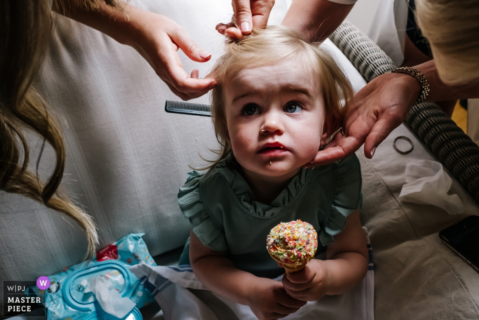 Photo by: <a href="https://www.wpja.com/contests/2019-v06/best-wedding-photographers/2489161">Kristian Leven - London</a> Flowergirl eats ice cream, whilst having her hair done as captured by Micklefield Hall wedding photographer.