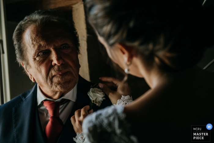 Foto von: <a href="https://www.wpja.com/contests/2019-v06/best-wedding-photographers/2492741"> Giuseppe De Angelis - Norma Latina </a> Castello di Montignano Hochzeitsfoto zeigt die Emotion des Vaters mit seiner Tochter, der Braut, als sie seine Blume auf seinen Mantel steckt