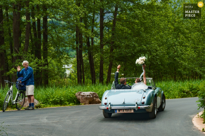 Zell Am See, Schloss Prielau, Austria Foto de una novia y un novio que se alejan en un auto convertible después de la ceremonia de boda.