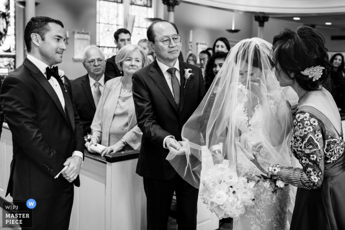Photo by: <a href="https://www.wpja.com/contests/2019-v06/best-wedding-photographers/2493021">JD Land - Marlton New Jersey</a> Old St. Joseph's Church Philadelphia Wedding Day Photography of Bride's Mom & Dad removing her veil while the Groom looks on.