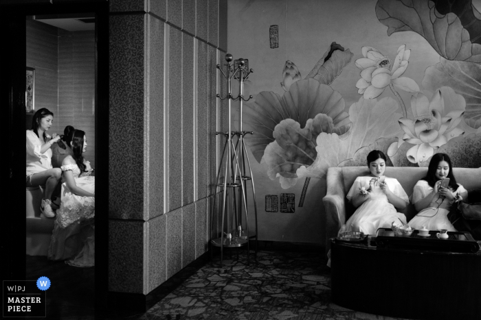 Photo by: <a href="https://www.wpja.com/contests/2019-v06/best-wedding-photographers/2493041">Lily Zeng - Longyan </a> Bridesmaids sit in another room while the bride gets her hair done on this black and white picture by a documentary-style Fujian, China wedding photographer.