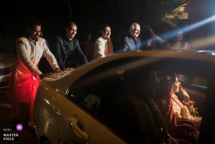 Gasten duwen het voertuig van de bruid en bruidegom terwijl ze afscheid nemen in deze bekroonde foto gemaakt door een huwelijksfotograaf in Mumbai.