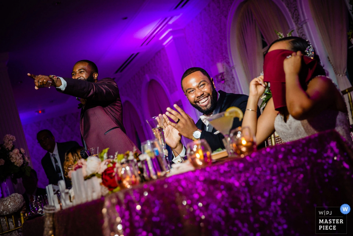 Photo by: <a href="https://www.wpja.com/contests/2019-v06/best-wedding-photographers/2495016">Miguel Gonzalez - Abington Pennsylvania</a> The Merion Wedding Photography | Best man told a story about the bride. She covers her face embarrassed.