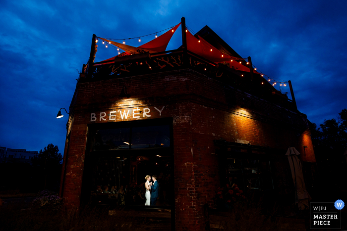 Foto van bruid en bruidegom die hun eerste dans samen delen tijdens hun huwelijksontvangst bij Briar Common Brewery in Denver, Colorado.