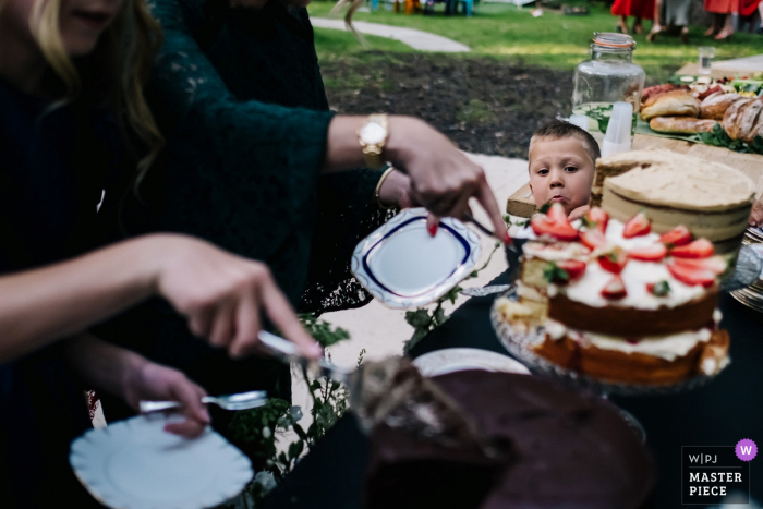 Trouwfoto van Longton Wood - De neef van de bruid kijkt toe terwijl gasten zich in de taart smullen