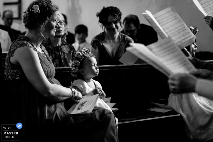Photo by: <a href="https://www.wpja.com/contests/2019-v07/best-wedding-photographers/2501501">Catherine Hill - Canterbury Kent</a> Wedding Photo from Petham Church, Petham, Kent, UK - A flower girl is mesmerized by the choir singing