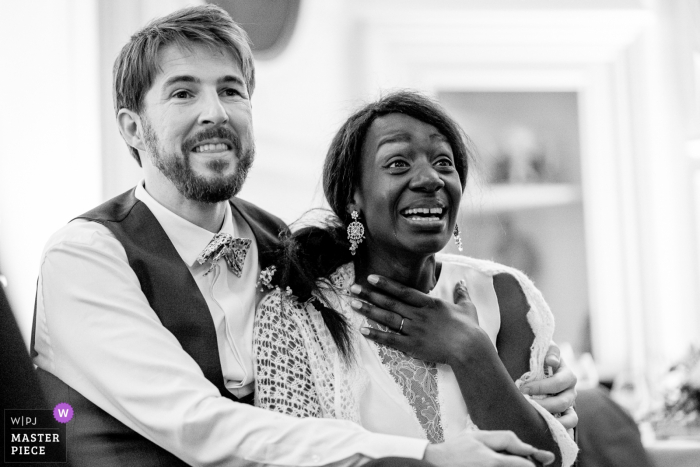 La novia se emociona al ver un video sorpresa preparado para ella y el novio durante su recepción en el Château d'Azy en esta fotografía de boda en blanco y negro compuesta por un galardonado fotógrafo de Nantes.