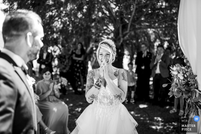 Foto door: <a href="https://www.wpja.com/contests/2019-v07/best-wedding-fotografen/2503176"> Luigi Rota - Comomeer Lecco </a> De bruid legt haar handen op haar gezicht als ze haar bruidegom op haar ziet wachten tijdens hun ceremonie in Villa le Due Torrette Erbailla in dit zwart-witbeeld dat een Lombardse huwelijksfotograaf heeft vastgelegd. s