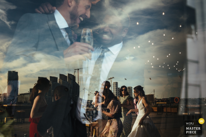 Photo by: <a href="https://www.wpja.com/contests/2019-v07/best-wedding-photographers/2503446">Lyndsey Goddard - London London</a> Wedding Photography from Trinity Buoy Wharf | Wedding guests and bride refelected in window