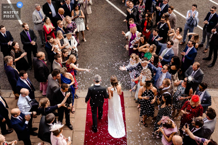 Photo by: <a href="https://www.wpja.com/contests/2019-v07/best-wedding-photographers/2504536">Stam Chananakhon - Phuket </a> Guests toss confetti at the bride and groom as they exit their London, England ceremony in this image captured by a Phuket, Thailand wedding photographer.