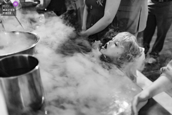 Foto door: <a href="https://www.wpja.com/contests/2019-v07/best-wedding-fotografen/2504766"> Philip Thomas - San Antonio Texas </a> Cypress, Texas - Bridal Oaks bruiloften en evenementen Wedding Photography - grappig moment van meisje blazen damp mist rond gekoeld ijs op een bruiloft receptie