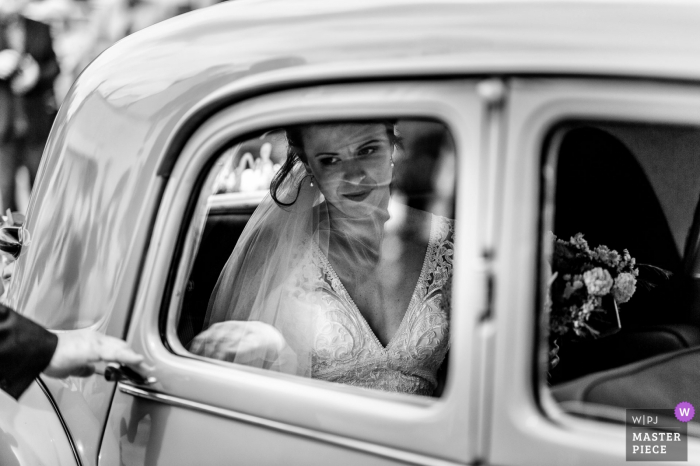 The bride prepares to exit her vehicle for the ceremony in Ploemeur, France in this black and white award-winning image by a Melbourne, Australia wedding photographer.