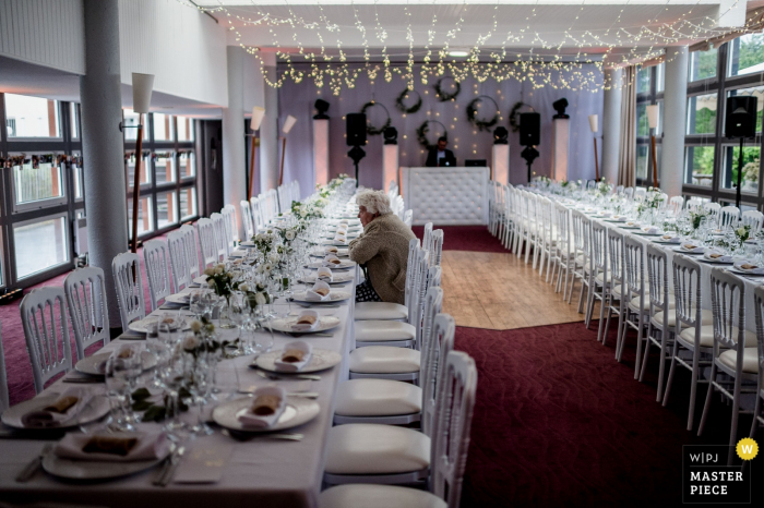 One guest takes a seat in the reception hall at Domaine de L'Abbatiale in Kerdréan, France in this wedding photo by a Melbourne, Australia photographer.