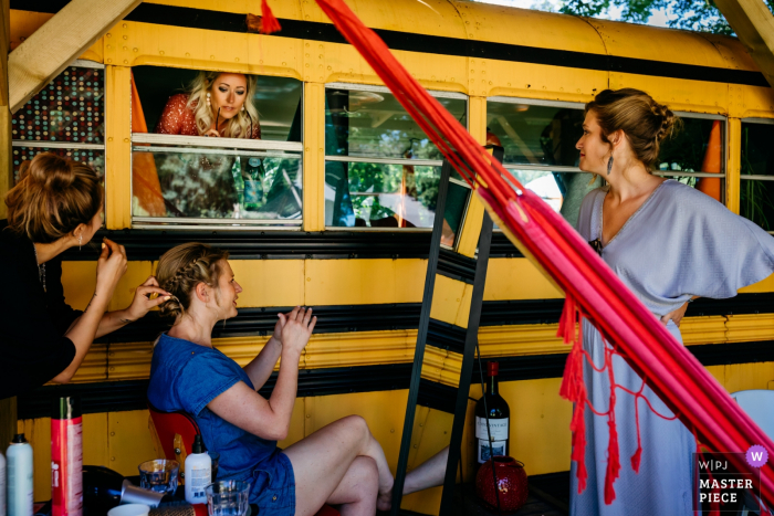 Photo by: <a href="https://www.wpja.com/contests/2019-v07/best-wedding-photographers/2505341">Leonard Walpot - Utrecht Utrecht</a> Women get ready for the ceremony by a school bus at Camping de Lievelinge in this picture created by a documentary-style Utrecht, Netherlands wedding photographer.