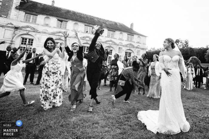 Photo by: <a href="https://www.wpja.com/contests/2019-v07/best-wedding-photographers/2505496">Simon Cassanas - Paris </a> Guests fight to catch the bride's bouquet at the Chateau Valery in this black and white wedding image composed by an award-winning Paris, France photographer.