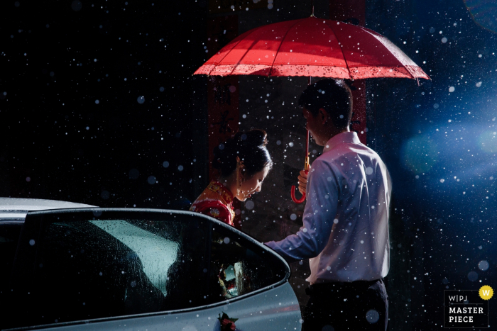 Photo by: <a href="https://www.wpja.com/contests/2019-v07/best-wedding-photographers/2505626">Joy Qin - Longyan </a> A man holds an umbrella over the bride as she steps out of her car and into the snowy night in this documentary-style photo by a Fujian, China wedding photographer.