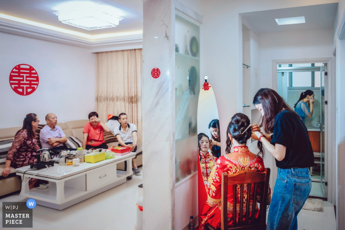 Photo by: <a href="https://www.wpja.com/contests/2019-v07/best-wedding-photographers/2505636">Joy Qin - Longyan </a> The bride gets her hair done while her family waits in the other room in this award-winning photo by a Fujian, China wedding photographer.