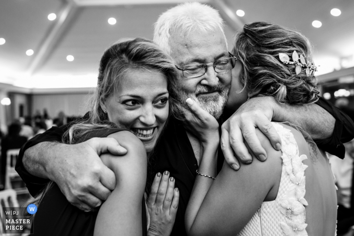 Photo by: <a href="https://www.wpja.com/contests/2019-v07/best-wedding-photographers/2505861">Antonio Calatayud - La Eliana Valencia</a> A father hugs the bride and her sister at El Puig in this black and white photo by a Valencia, Spain documentary wedding photographer.