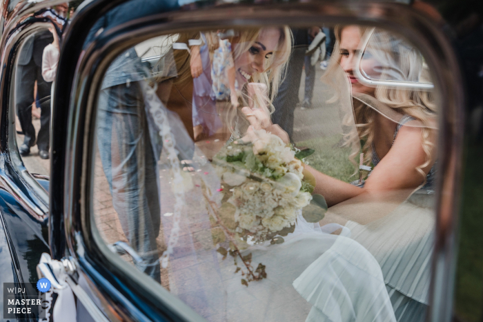 Photo by: <a href="https://www.wpja.com/contests/2019-v07/best-wedding-photographers/2506416">Nadine Lotze - Hagen Nordrhein-Westfalen</a> The bride is photographed through the car window as she exits her Kirche Bollensen Uslar ceremony in this award-winning photo by a Hagen, North Rhine-Westphalia wedding photographer.