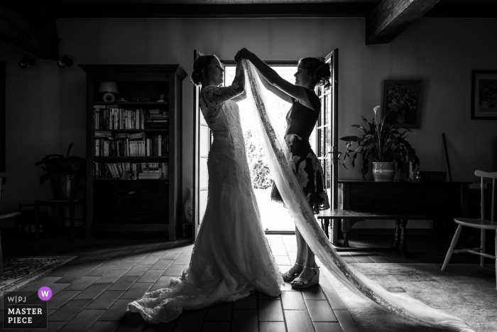 Photo by: <a href="https://www.wpja.com/contests/2019-v07/best-wedding-photographers/2506546">Henri Deroche - Orléans </a> The bride's sister helps her with her veil before her wedding at Neuville-aux-bois in this black and white photo by an award-winning Centre-Val de Loire, France wedding photographer.